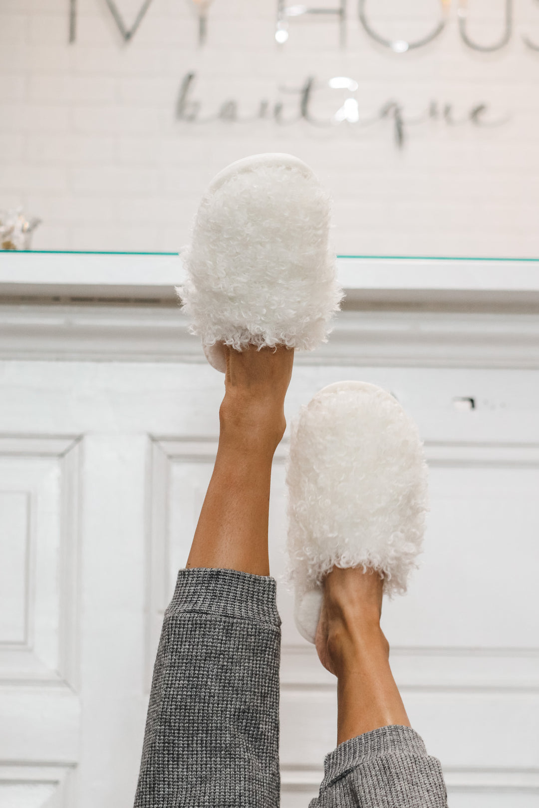 A photo of a woman wearing white furry slippers.